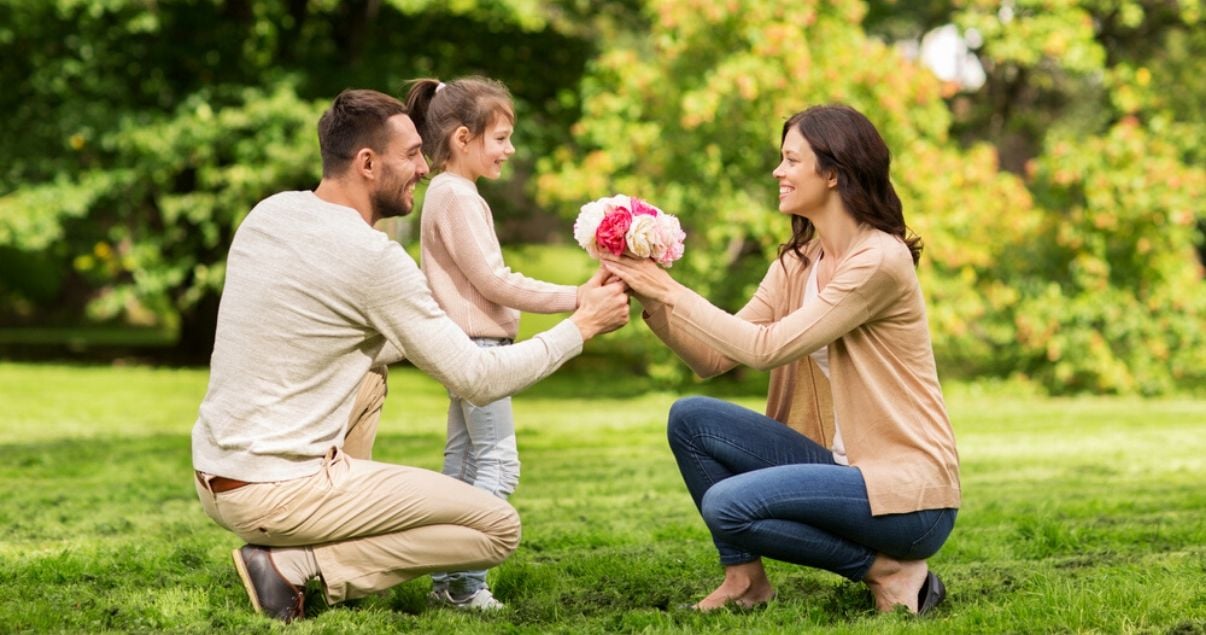 Hombre y niña dandole un ramo de flores rosas y blancas a una mujer usando sustantivos en ingles