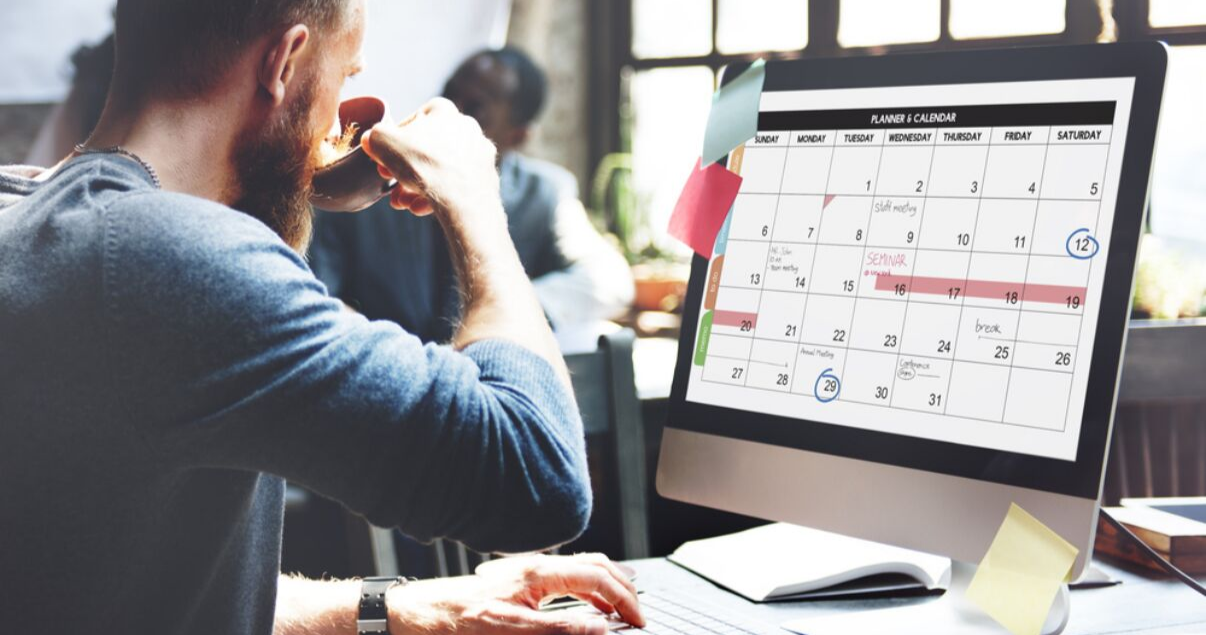 hombre en sweater sentado en la oficina con calendario para planificar aprender inglés