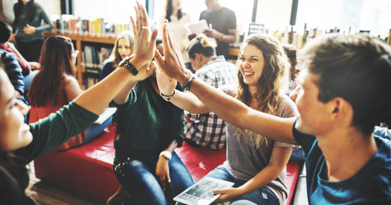 Amigos en una biblioteca estudiando cómo utilizar los slangs en inglés festejando porque estan adquiriendo vocabulario en inglés