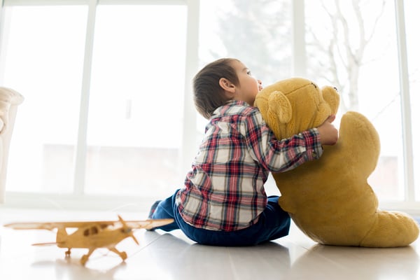 Little baby kid sitting in living room with toy bear