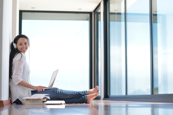 beautiful young woman relax and work on laptop computer while listening music on heaphones and read book at home
