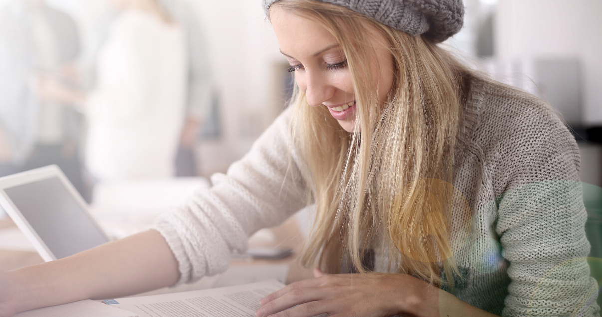 Una mujer joven concentrada con su ipad en un cafe aprendiendo sobre gramática en inglés
