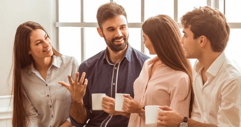 hombre hablando felizmente en ingles para el trabajo con colegas y tomando cafe en el pasillo de la oficina