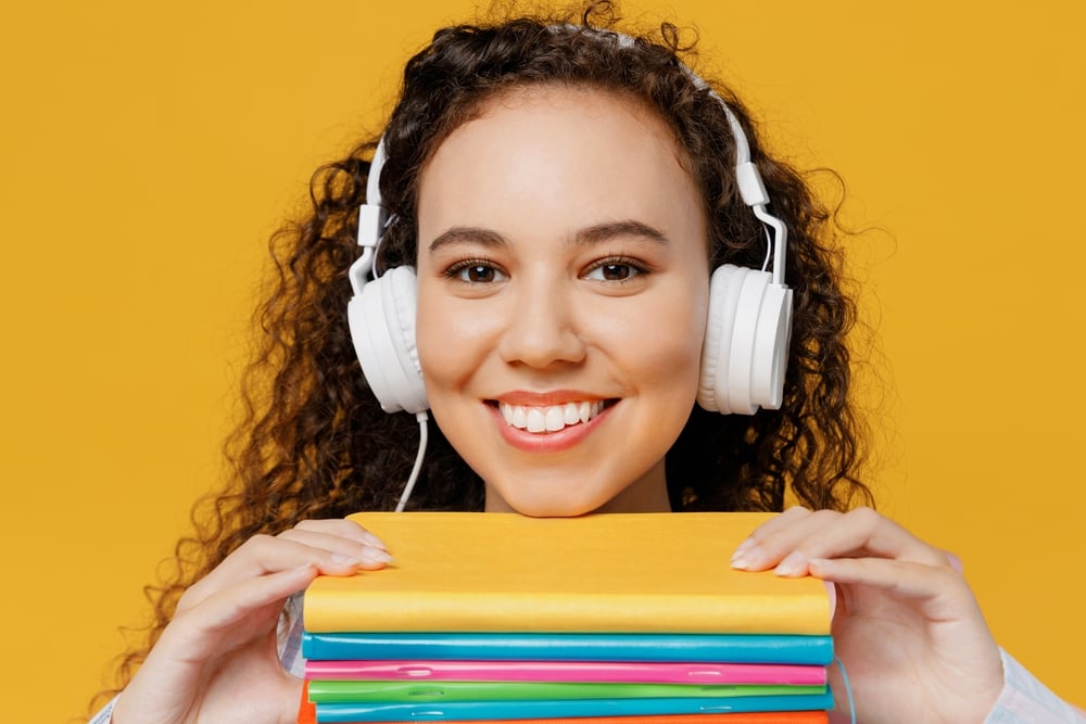 Joven mujer escucha audiobooks para estudiar inglés en la adolescencia.